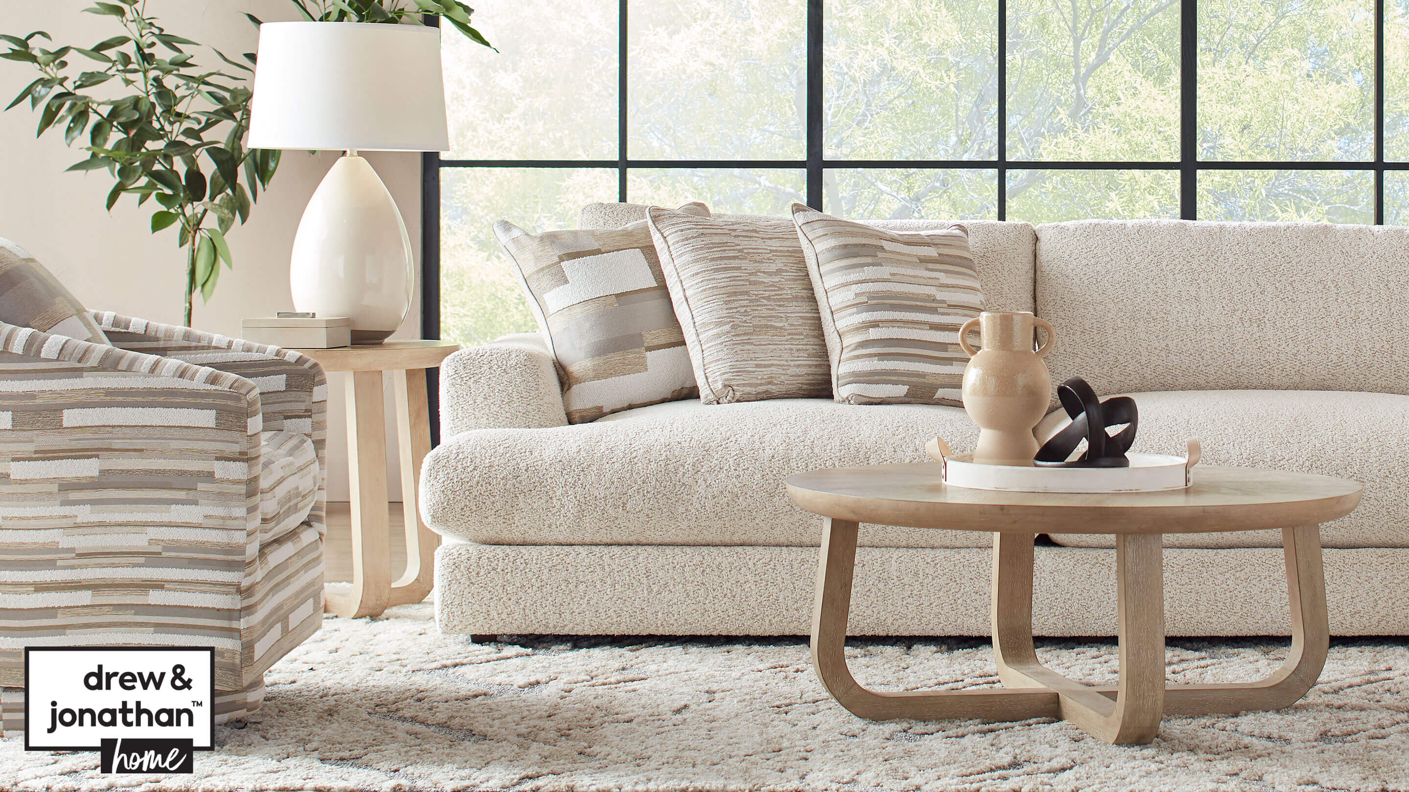 Living room scene with Shaw coffee table and end table. Montecito sofa in with three accent pillows, and Montecito accent chair in multi colored cream and tan pattern.